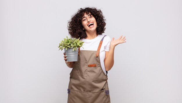 Jovem jardineira sentindo-se feliz, excitada, surpresa ou chocada, sorrindo e atônita com algo inacreditável