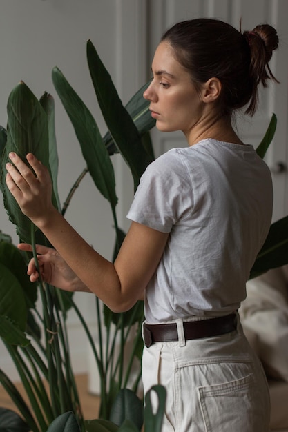 Jovem jardineira tocando plantas de casa exuberantes plantas de amor hobby conceito de jardinagem em casa freelancer