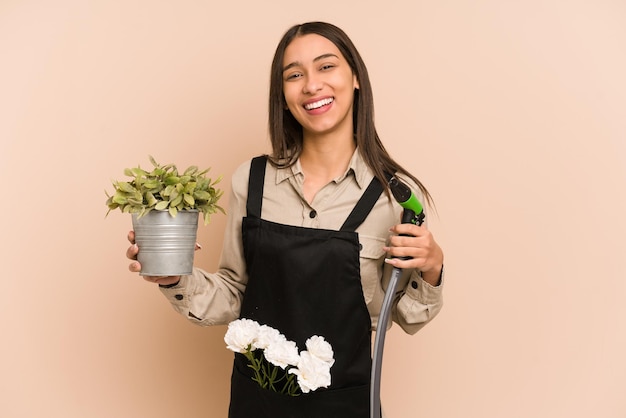 Jovem jardineiro colombiano segura uma planta e uma mangueira, cuidando da natureza.