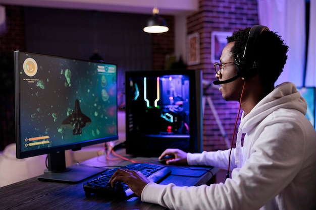 Jovem jogador jogando videogames de tiro online, streaming de competição de rpg de ação no pc com luzes de neon. Serpentina masculina se divertindo com o campeonato de jogos esport no computador.