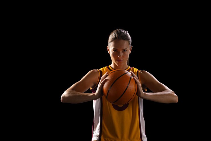 Foto jovem jogadora de basquete caucasiana segura uma bola de basquetebol com confiança em um fundo preto
