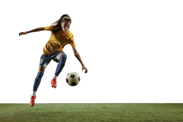 Jovem jogadora de futebol ou futebol americano com cabelo comprido em roupas esportivas e botas, chutando bola