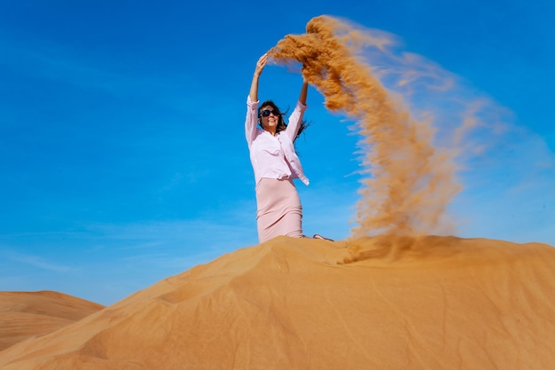 Jovem jogando areia no deserto de orande