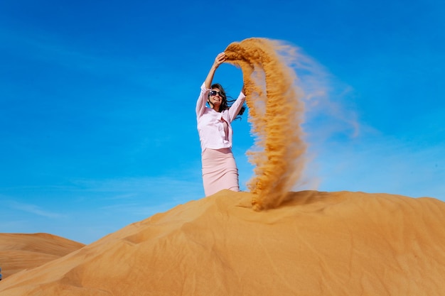 Jovem jogando areia no deserto de orande