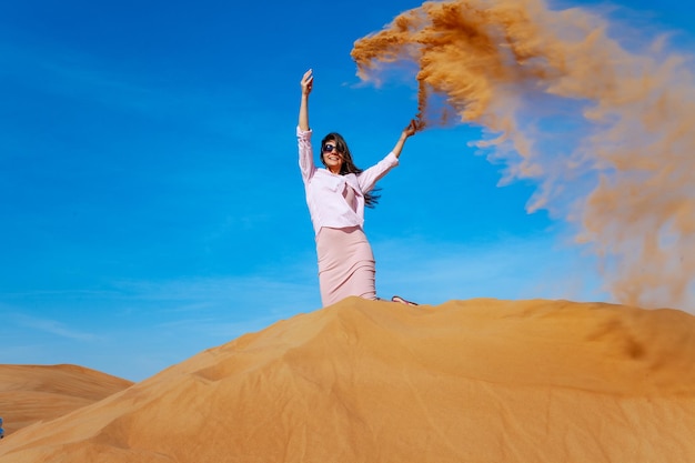 Jovem jogando areia no deserto de orande