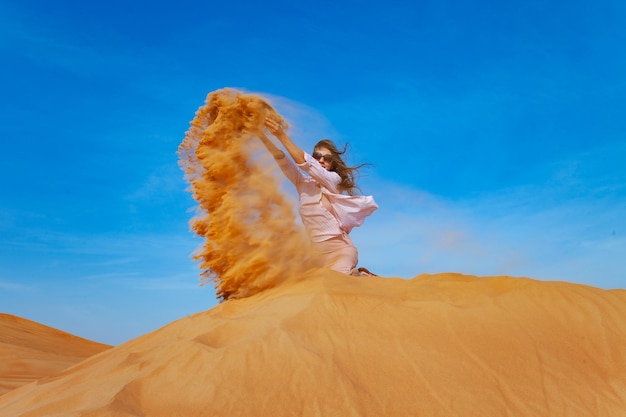 Jovem jogando areia no deserto de orande