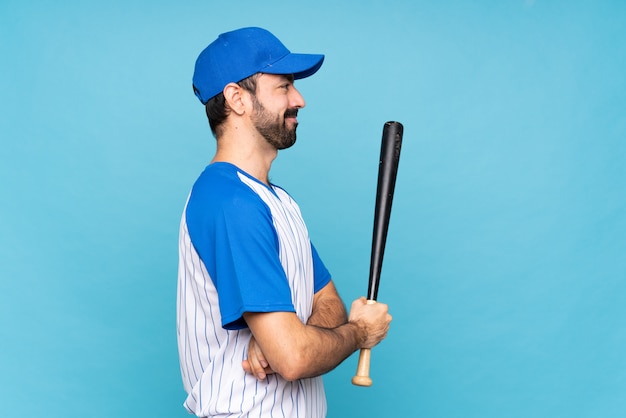 Jovem jogando beisebol sobre azul isolado na posição lateral