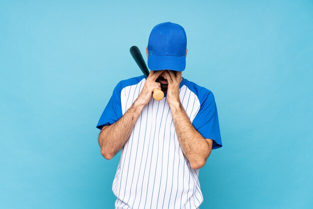 Jovem jogando beisebol sobre parede azul isolada com expressão cansada e doente