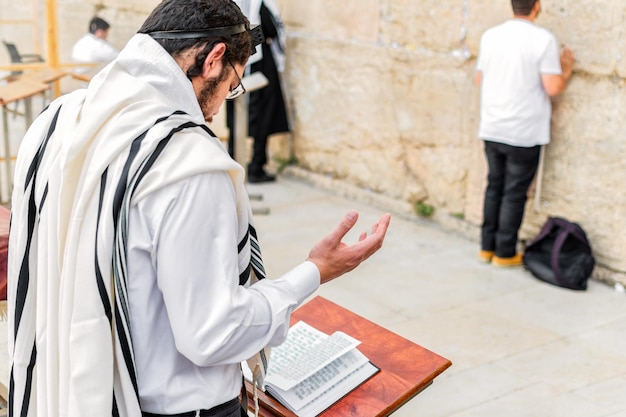 Jovem judeu ortodoxo orando com tefilins filactérios no muro occidental
