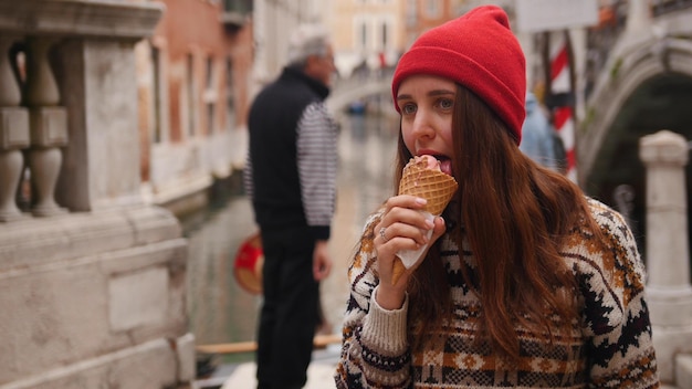 Jovem lambe o sorvete enquanto caminha pelas ruas de Veneza