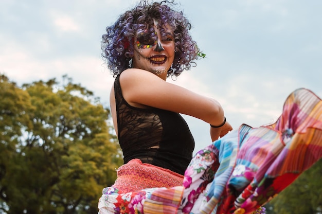 Jovem latina com maquiagem La Calavera Catrina ao ar livre dançando danças tradicionais