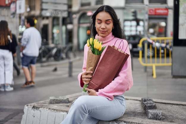 Jovem latina com tulipas amarelas e vinho espalhando amor e alegria através de uma surpresa romântica