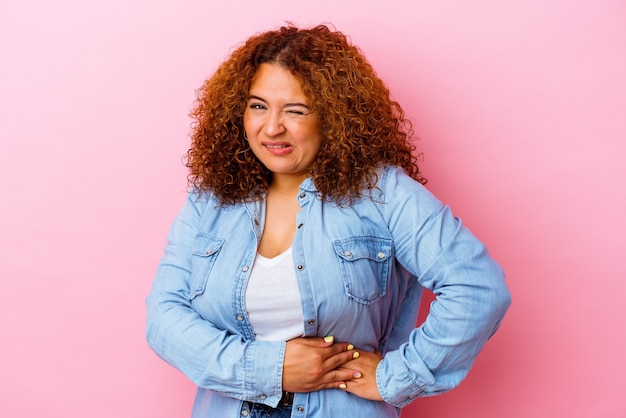 Jovem latina curvilínea mulher isolada na parede rosa, tendo uma dor no fígado, dor de estômago.