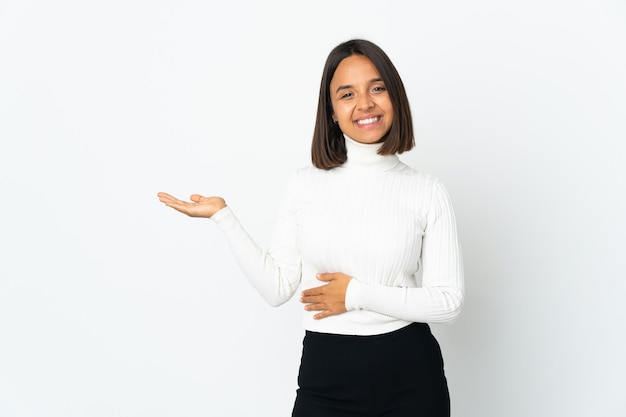 Foto jovem latina isolada no fundo branco apresentando uma ideia enquanto olha sorrindo para