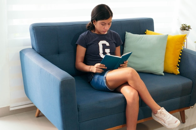 Jovem latina lendo um livro enquanto está sentada em casa