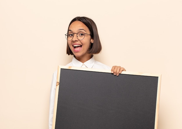 Jovem latina parecendo feliz e agradavelmente surpresa, animada com uma expressão de fascínio e choque