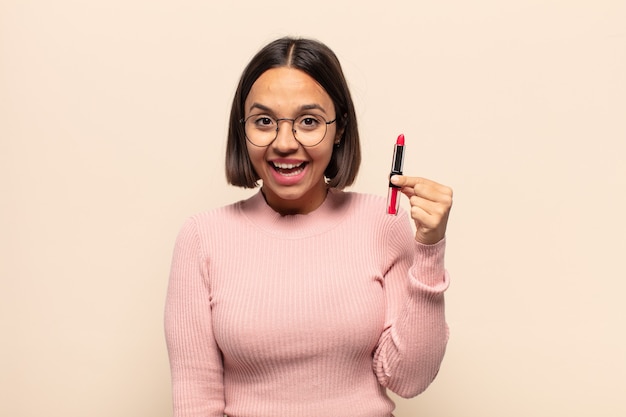 Jovem latina parecendo feliz e agradavelmente surpresa, animada com uma expressão de fascínio e choque