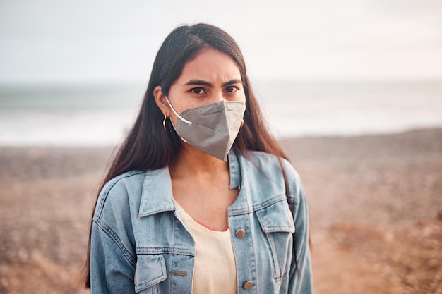 Jovem latina posa andando na areia durante um belo pôr do sol Jovem feliz com máscara