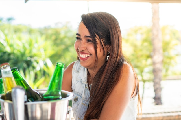 Foto jovem latina se divertindo com seus amigos bebendo uma garota hispânica sorridente tomando algumas cervejas