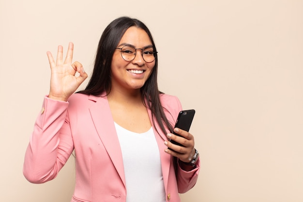 Jovem latina se sentindo feliz, relaxada e satisfeita, mostrando aprovação com gesto de ok, sorrindo