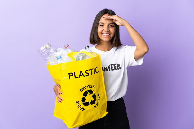 Jovem latina segurando uma sacola de reciclagem cheia de papel para reciclar