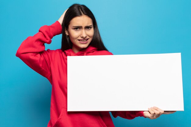 Foto jovem latina sentindo-se estressada, preocupada, ansiosa ou assustada, com as mãos na cabeça, entrando em pânico com o erro