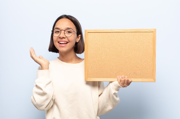 Jovem latina sentindo-se feliz, surpresa e alegre, sorrindo com atitude positiva, percebendo uma solução ou ideia