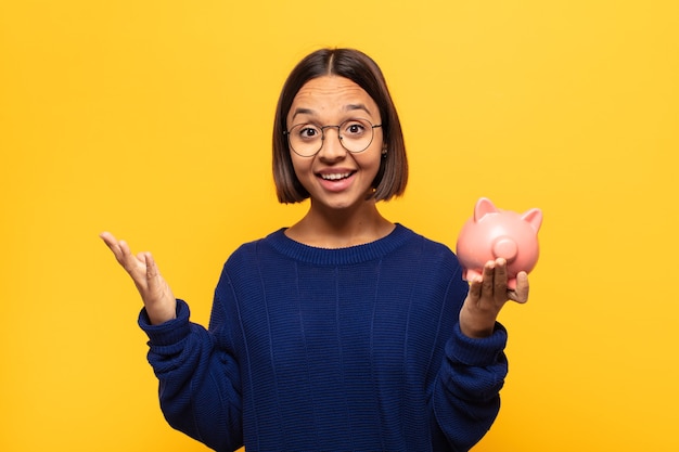 Jovem latina sentindo-se feliz, surpresa e alegre, sorrindo com atitude positiva, percebendo uma solução ou ideia