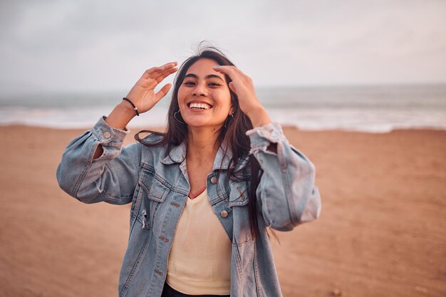 Jovem latina sorri durante um belo pôr do sol Jovem feliz com máscara na praia tomando