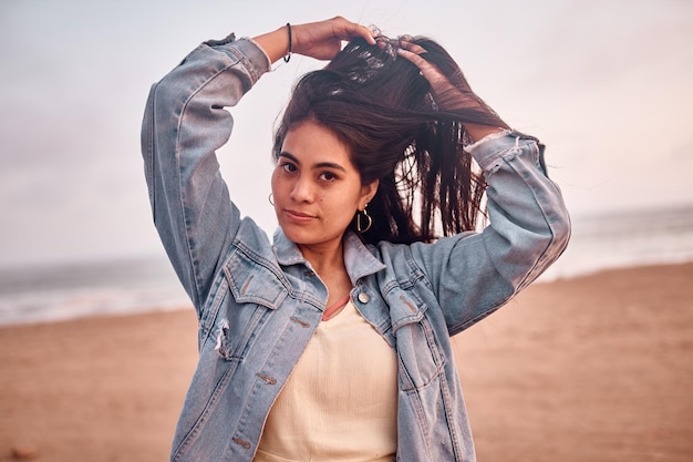 Jovem latina sorri durante um belo pôr do sol Jovem feliz com máscara na praia tomando