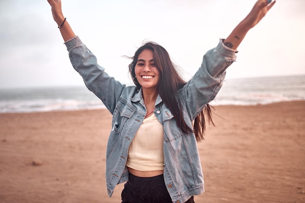 Foto jovem latina sorri durante um belo pôr do sol jovem feliz com máscara na praia tomando