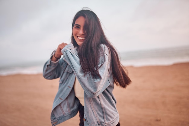 Jovem latina sorri durante um belo pôr do sol jovem feliz com máscara na praia tomando