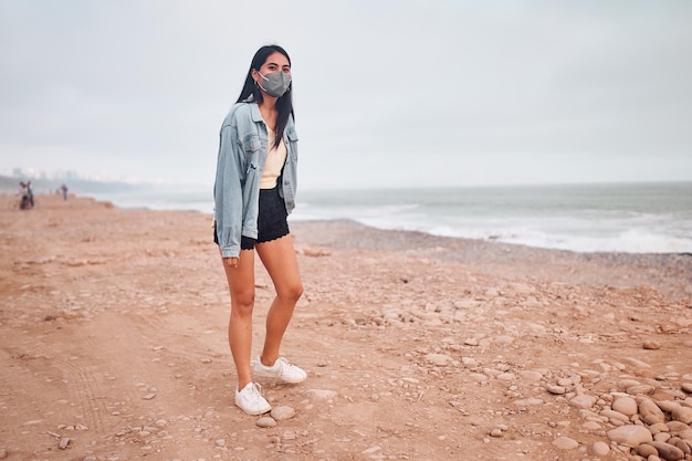 Foto jovem latina sorri durante um belo pôr do sol jovem feliz com máscara na praia tomando