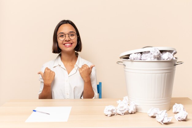 Foto jovem latina sorrindo com alegria e parecendo feliz, sentindo-se despreocupada e positiva com os dois polegares para cima