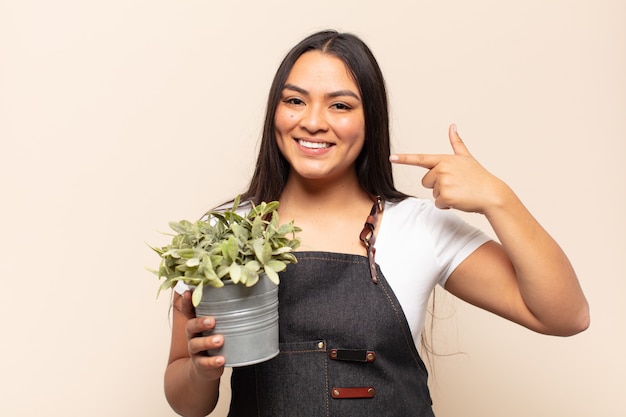 Jovem latina sorrindo com confiança apontando para o próprio sorriso largo, atitude positiva, relaxada e satisfeita