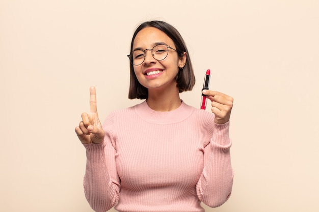 Jovem latina sorrindo com orgulho e confiança fazendo a pose número um triunfantemente, sentindo-se uma líder