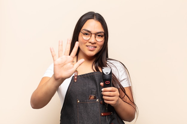 Jovem latina sorrindo e parecendo amigável, mostrando o número cinco ou quinto com a mão para a frente, em contagem regressiva