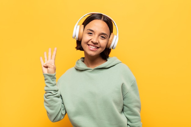 Jovem latina sorrindo e parecendo amigável, mostrando o número quatro ou o quarto com a mão para a frente, em contagem regressiva