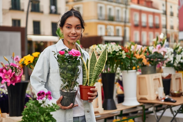 Jovem latina sorrindo enquanto comprava plantas na barraca de um vendedor ambulante