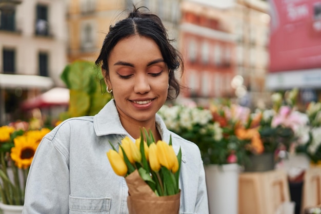 Jovem latina sorrindo enquanto comprava tulipas amarelas na banca de um vendedor ambulante