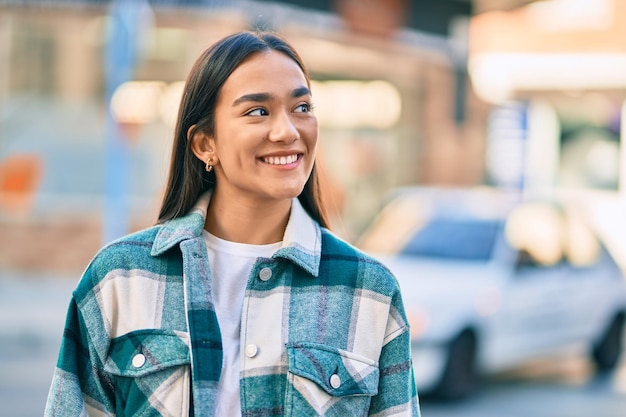 Jovem latina sorrindo feliz em pé na cidade.