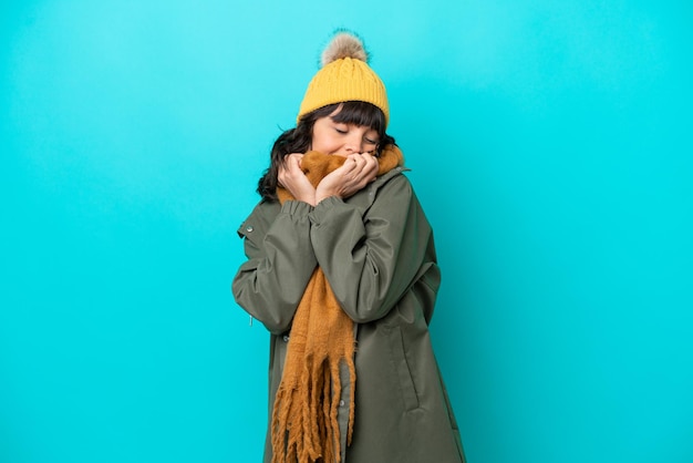 Jovem latina vestindo jaqueta de inverno isolada em fundo azul