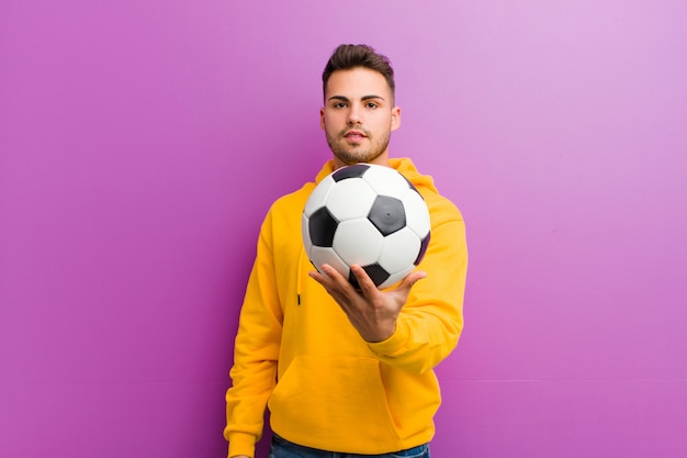 Jovem latino-americano com uma bola de futebol em roxo