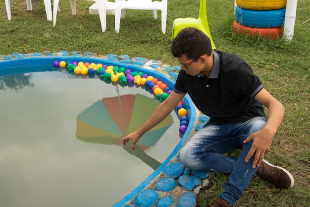 Jovem latino colombiano brincando com água em uma piscina