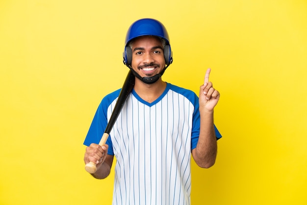 Jovem latino colombiano jogando beisebol isolado em um fundo amarelo apontando uma ótima ideia