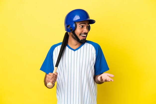 Jovem latino colombiano jogando beisebol isolado em um fundo amarelo com expressão de surpresa ao olhar para o lado