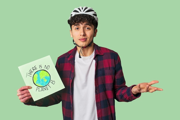 Jovem latino com um capacete de bicicleta segurando um sinal de que não há planta b