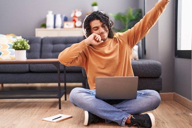 Jovem latino dançando e ouvindo música sentado no chão em casa