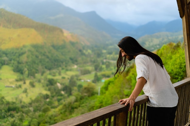 Jovem latino de cabelos compridos em um ponto de vista na colômbia Quindio aproveitando o espaço de cópia da paisagem montanhosa