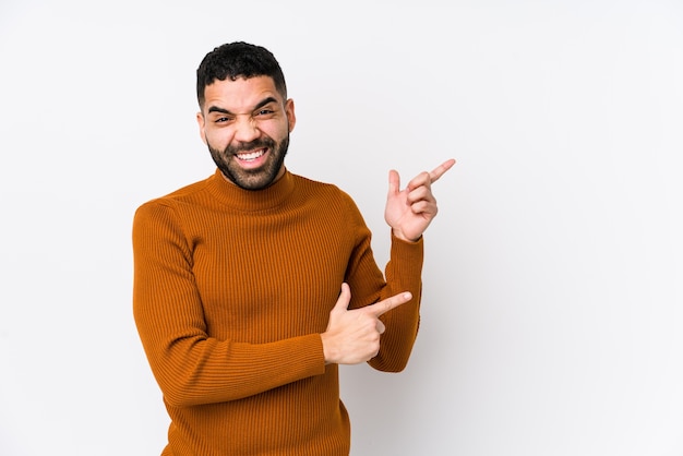 Jovem latino em branco isolado apontando com os indicadores para um espaço de cópia, expressando entusiasmo e desejo.